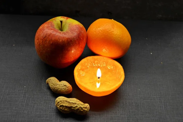 Koyu arka planda turuncu kabuğu fındık ve mum ile meyveler