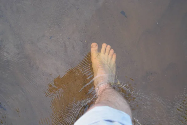 Standing with the naked feet in the water