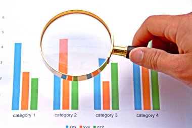 Bir istatistikte büyüteçle işaret eden adam 