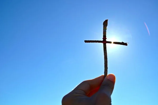 holding a self made wooden cross in the hand