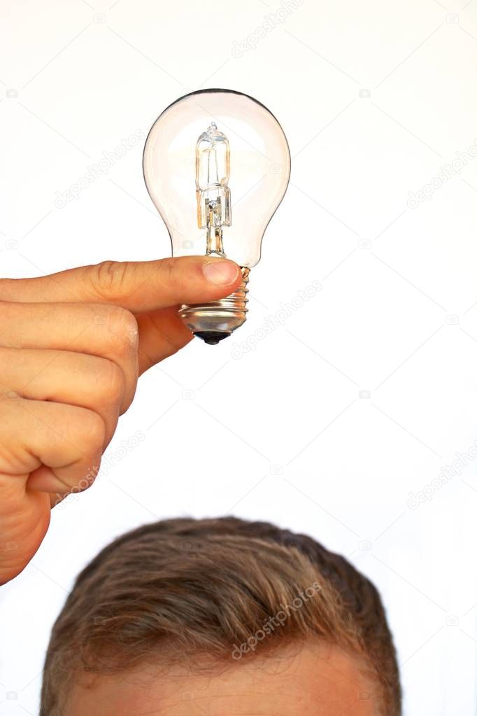 Hand holding a light bulb over a head