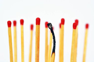 Yanmış bir maç beyaz bir arka plan karşı duruyor, yanında ve arkasında kırmızı kafaları ile bozulmamış maçlar vardır. Tükenmişlik ve tükenme kavramı