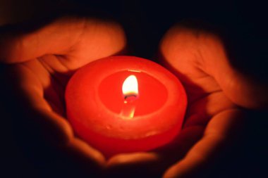 karanlıkta kırmızı bir mum tutarak yakın