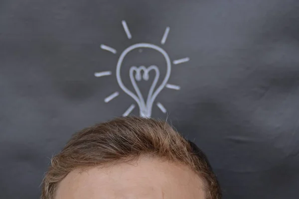 head in front of a board with a drawn lamp on