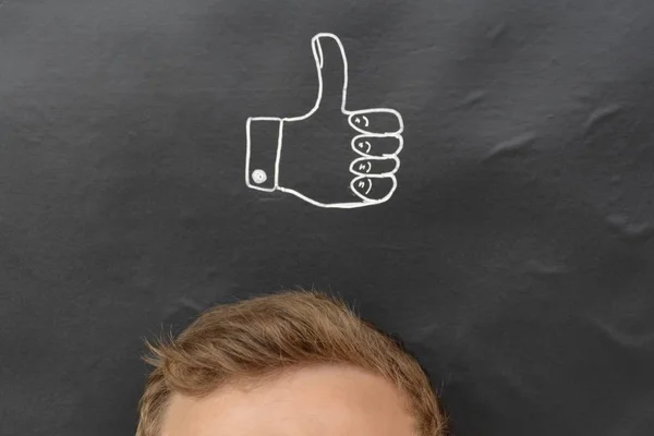 head in front of a board with drawn thumb up