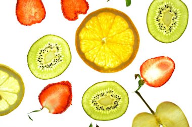 Portakal, çilek ve kivi gibi farklı dilimlenmiş meyveler parlak beyaz bir arka plan üzerinde yatıyor ve ışık ile yukarıdan aydınlatılır - farklı renklerde taze ve sağlıklı meyve kavramı