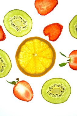 Portakal, çilek ve kivi gibi farklı dilimlenmiş meyveler parlak beyaz bir arka plan üzerinde yatıyor ve ışık ile yukarıdan aydınlatılır - farklı renklerde taze ve sağlıklı meyve kavramı