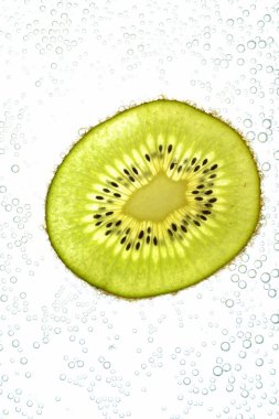 Bir dilimlenmiş kivi hafif bir arka plan üzerinde yatıyor - ince kivi dilimleri ile aşağıdan aydınlatılır 