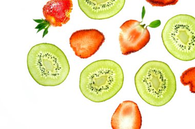 Bir dilimlenmiş kivi ve dilimlenmiş çilek yukarıdan aydınlatılmış beyaz parlak bir arka plan üzerinde yatıyor - taze meyve ile kavram 