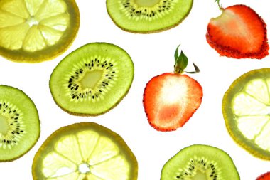 Portakal, çilek ve kivi gibi farklı dilimlenmiş meyveler parlak beyaz bir arka plan üzerinde yatıyor ve ışık ile yukarıdan aydınlatılır - farklı renklerde taze ve sağlıklı meyve kavramı - 