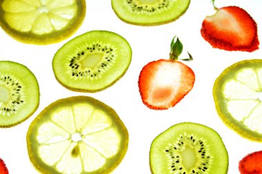 Portakal, çilek ve kivi gibi farklı dilimlenmiş meyveler parlak beyaz bir arka plan üzerinde yatıyor ve ışık ile yukarıdan aydınlatılır - farklı renklerde taze ve sağlıklı meyve kavramı - 