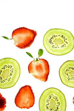 Bir dilimlenmiş kivi ve dilimlenmiş çilek yukarıdan aydınlatılmış beyaz parlak bir arka plan üzerinde yatıyor - taze meyve ile kavram 