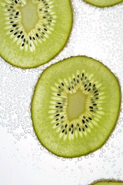 Bir dilimlenmiş kivi hafif bir arka plan üzerinde yatıyor - ince kivi dilimleri ile aşağıdan aydınlatılır 