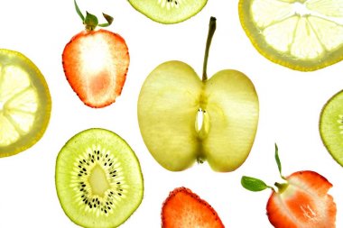 Portakal, çilek ve kivi gibi farklı dilimlenmiş meyveler parlak beyaz bir arka plan üzerinde yatıyor ve ışık ile yukarıdan aydınlatılır - farklı renklerde taze ve sağlıklı meyve kavramı - 