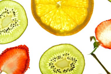 Portakal, çilek ve kivi gibi farklı dilimlenmiş meyveler parlak beyaz bir arka plan üzerinde yatıyor ve ışık ile yukarıdan aydınlatılır - farklı renklerde taze ve sağlıklı meyve kavramı