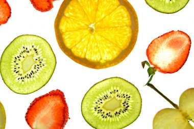 Portakal, çilek ve kivi gibi farklı dilimlenmiş meyveler parlak beyaz bir arka plan üzerinde yatıyor ve ışık ile yukarıdan aydınlatılır - farklı renklerde taze ve sağlıklı meyve kavramı