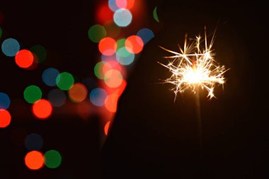 renkli bir peri ışıkları önünde bir donanma fişeği tutarak