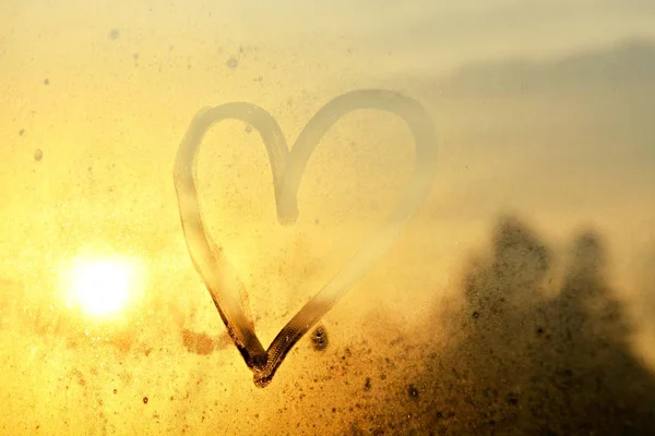 heart on a fogged window in the sunset