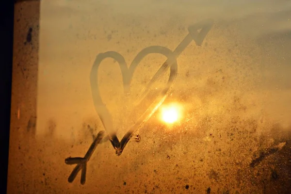 heart on a fogged window in the sunset