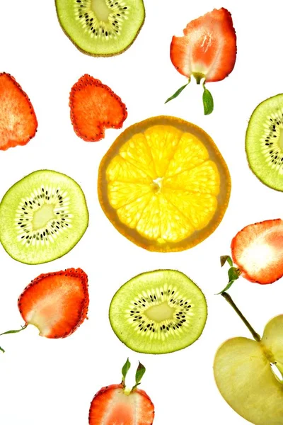 오렌지 키위와 슬라이스 과일은 배경에 있으며 빛으로 위에서 조명됩니다 색상의 — 스톡 사진