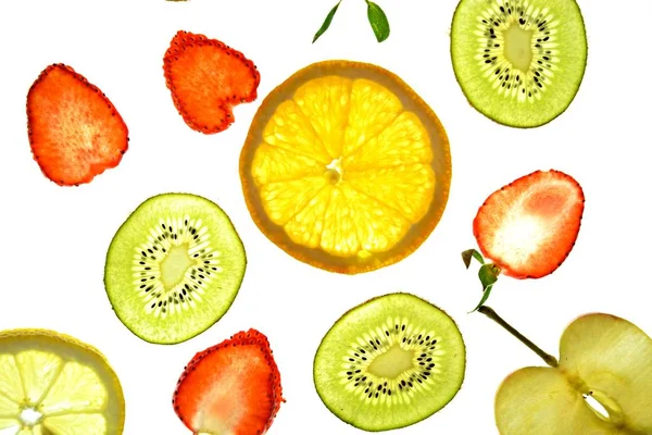 オレンジ イチゴ キウイのような異なるスライスされた果物は 明るい白い背景に位置し 光で上から照らされています 異なる色で新鮮で健康的な果物とのコンセプト — ストック写真