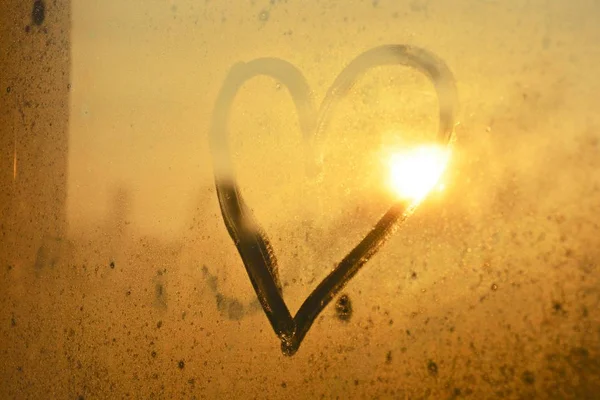 heart on a fogged window in the sunset