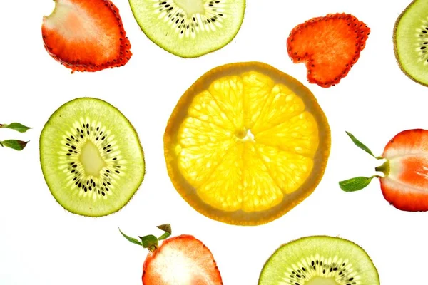 オレンジ イチゴ キウイのような異なるスライスされた果物は 明るい白い背景に位置し 光で上から照らされています 異なる色で新鮮で健康的な果物とのコンセプト — ストック写真