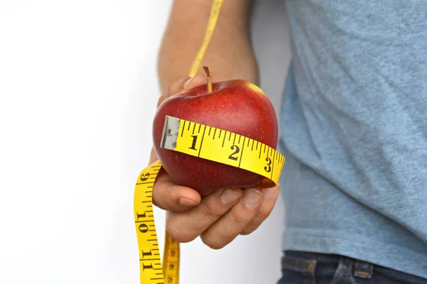 Holding an apple wrapped up with measuring tape in the hand