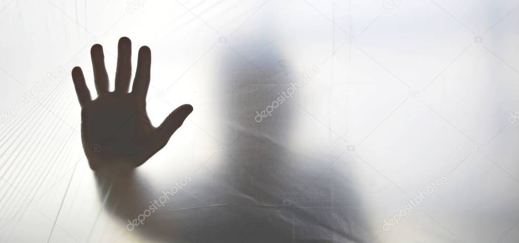 Silhouette of a ghost hand behind transparent plastic 