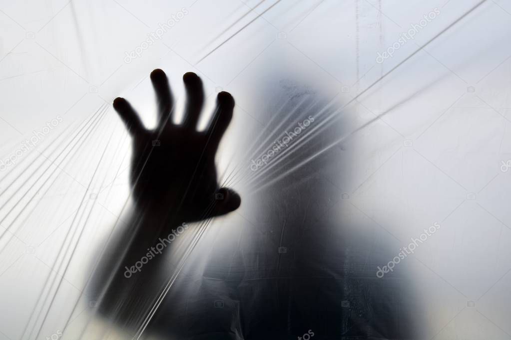 Silhouette of a ghost hand behind transparent plastic 