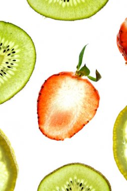 Portakal, çilek ve kivi gibi farklı dilimlenmiş meyveler parlak beyaz bir arka plan üzerinde yatıyor ve ışık ile yukarıdan aydınlatılır - farklı renklerde taze ve sağlıklı meyve kavramı - 