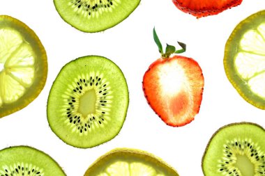 Portakal, çilek ve kivi gibi farklı dilimlenmiş meyveler parlak beyaz bir arka plan üzerinde yatıyor ve ışık ile yukarıdan aydınlatılır - farklı renklerde taze ve sağlıklı meyve kavramı - 