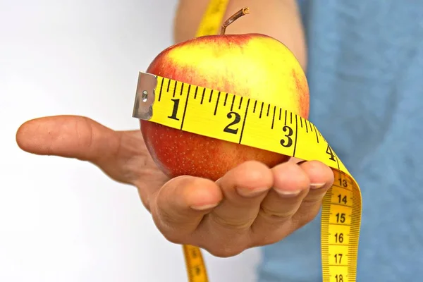 測定テープで包まれたリンゴを手に持つ — ストック写真
