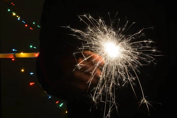 色付きのライトの前の夜のスパークラー 大晦日に スパークラーはゆっくりと燃え尽き すべての方向に火花を散らします — ストック写真