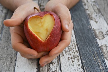 Elinde kesilmiş bir kalp şekli ile elma tutma