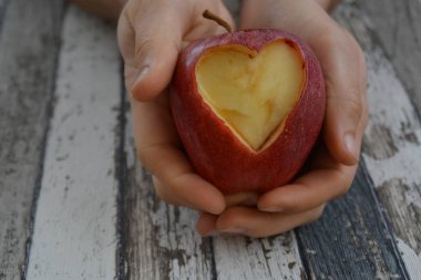 Elinde kesilmiş bir kalp şekli ile elma tutma