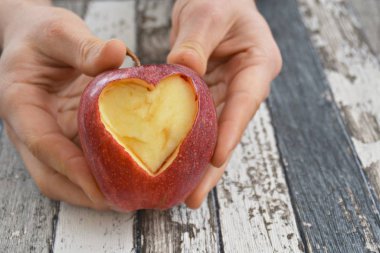 Elinde kesilmiş bir kalp şekli ile elma tutma