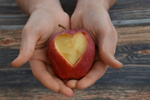 Holding apple with a heart shape cut out in the hand