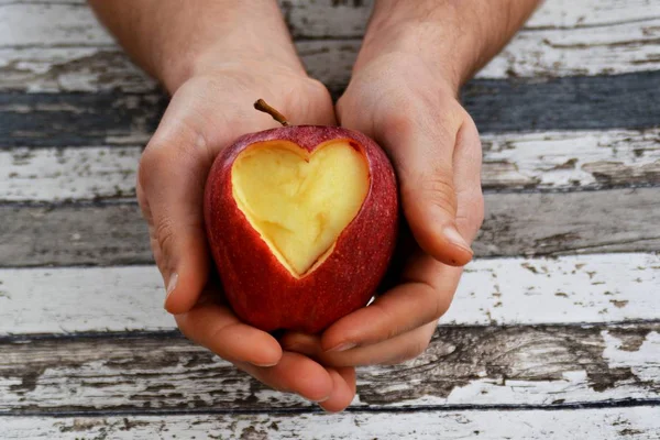 Holding apple with a heart shape cut out in hands