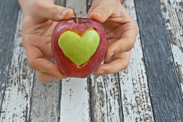 Holding apple with a heart shape cut out in the hand