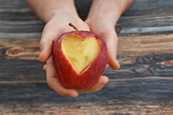 Holding apple with a heart shape cut out in the hand