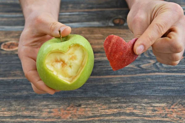 Holding apple with a heart shape cut out in the hand