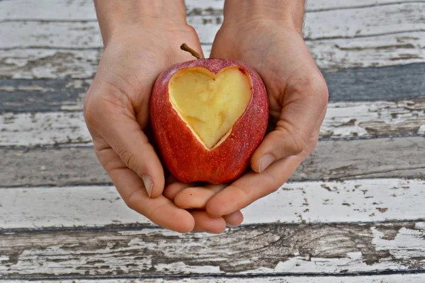 Holding apple with a heart shape cut out in hands