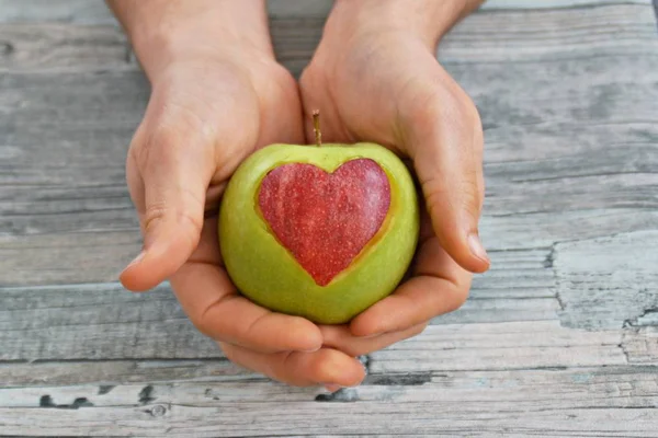 Holding apple with a heart shape cut out in the hand
