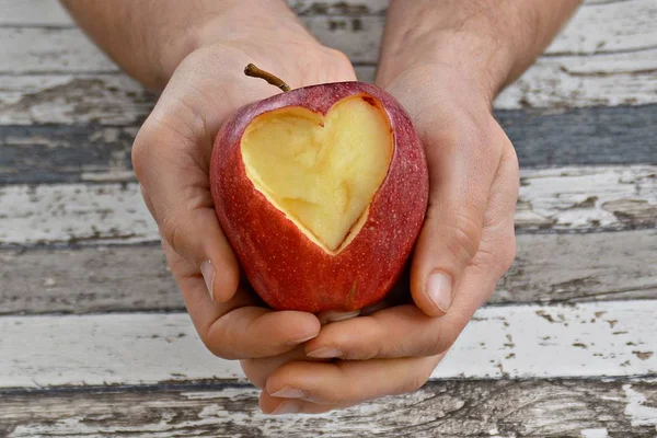 Holding apple with a heart shape cut out in hands