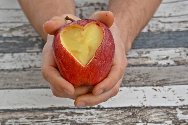 Holding apple with a heart shape cut out in hands