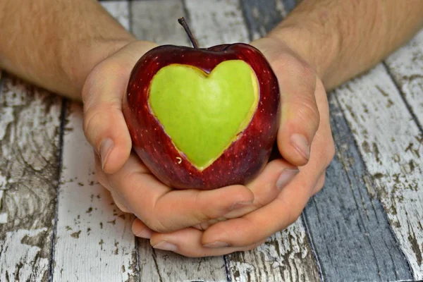 Holding apple with a heart shape cut out in hands