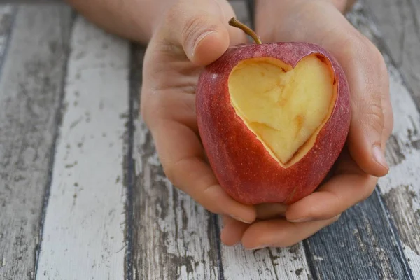 Holding apple with a heart shape cut out in hands