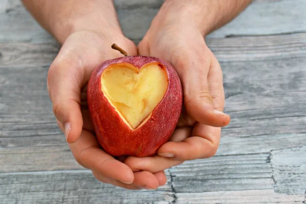 Holding apple with a heart shape cut out in hands