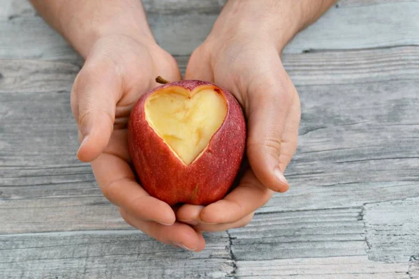 Holding apple with a heart shape cut out in hands